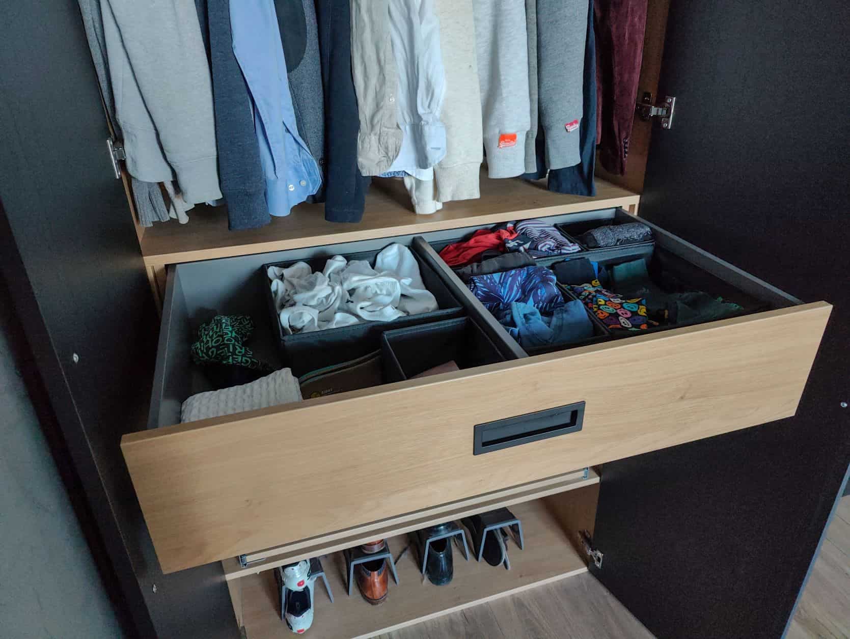 Lade met georganiseerde kleding en accessoires in een ingebouwde zwarte kledingkast in Blaricum.