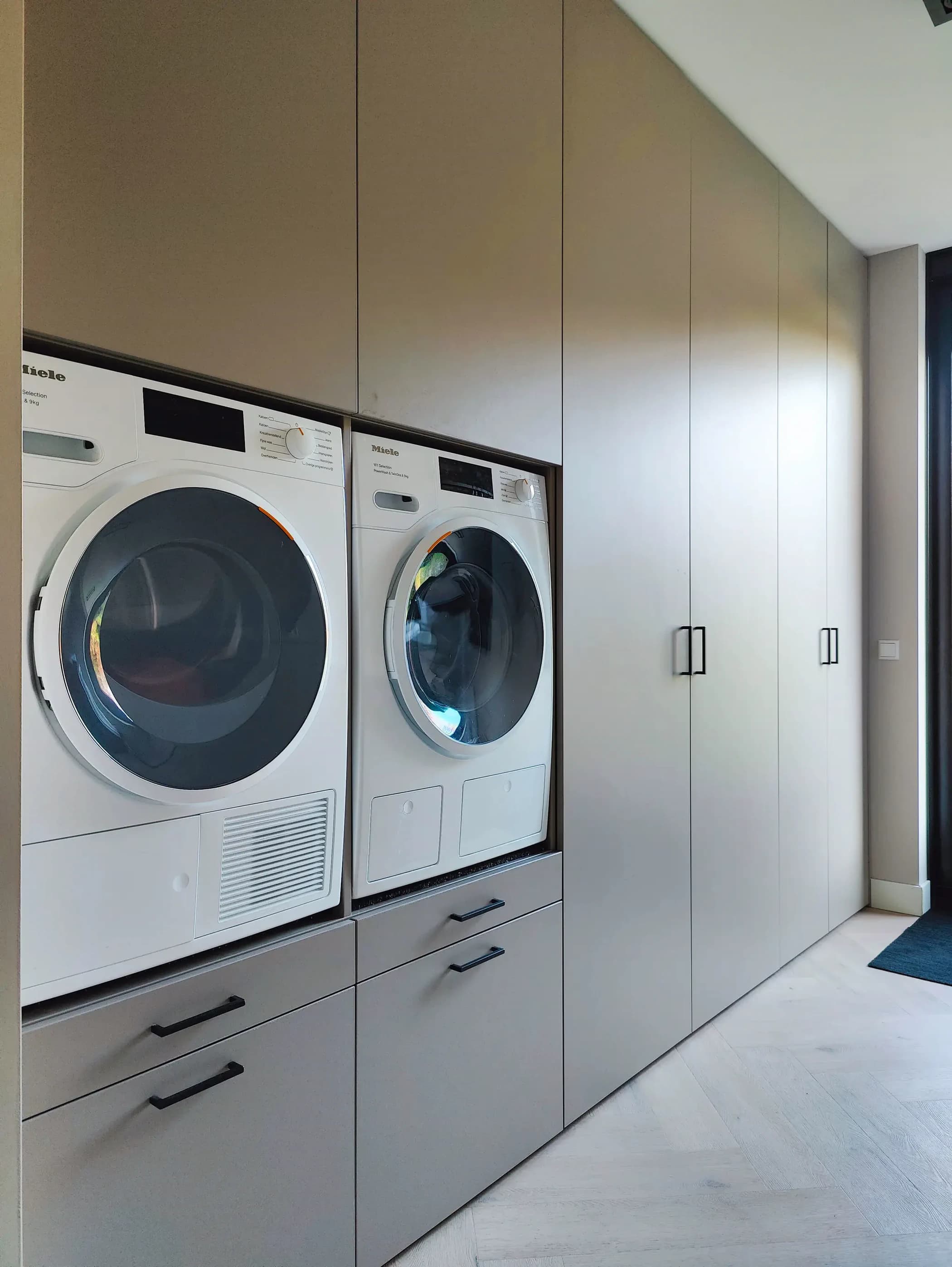 Moderne bijkeuken kast met zwarte grepen en lichte fronten