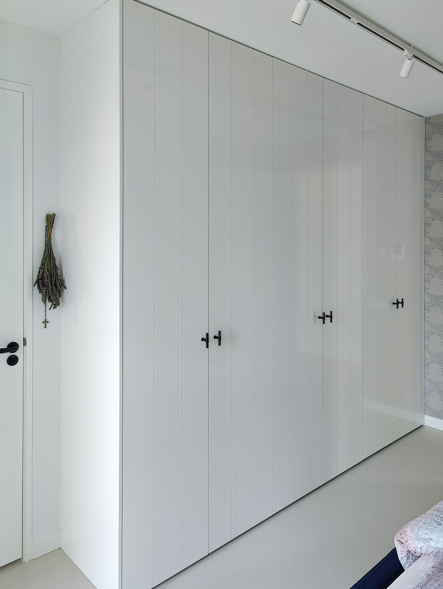 Dichtgeklapte witte hoogglans kledingkast met subtiele verticale lijnen.