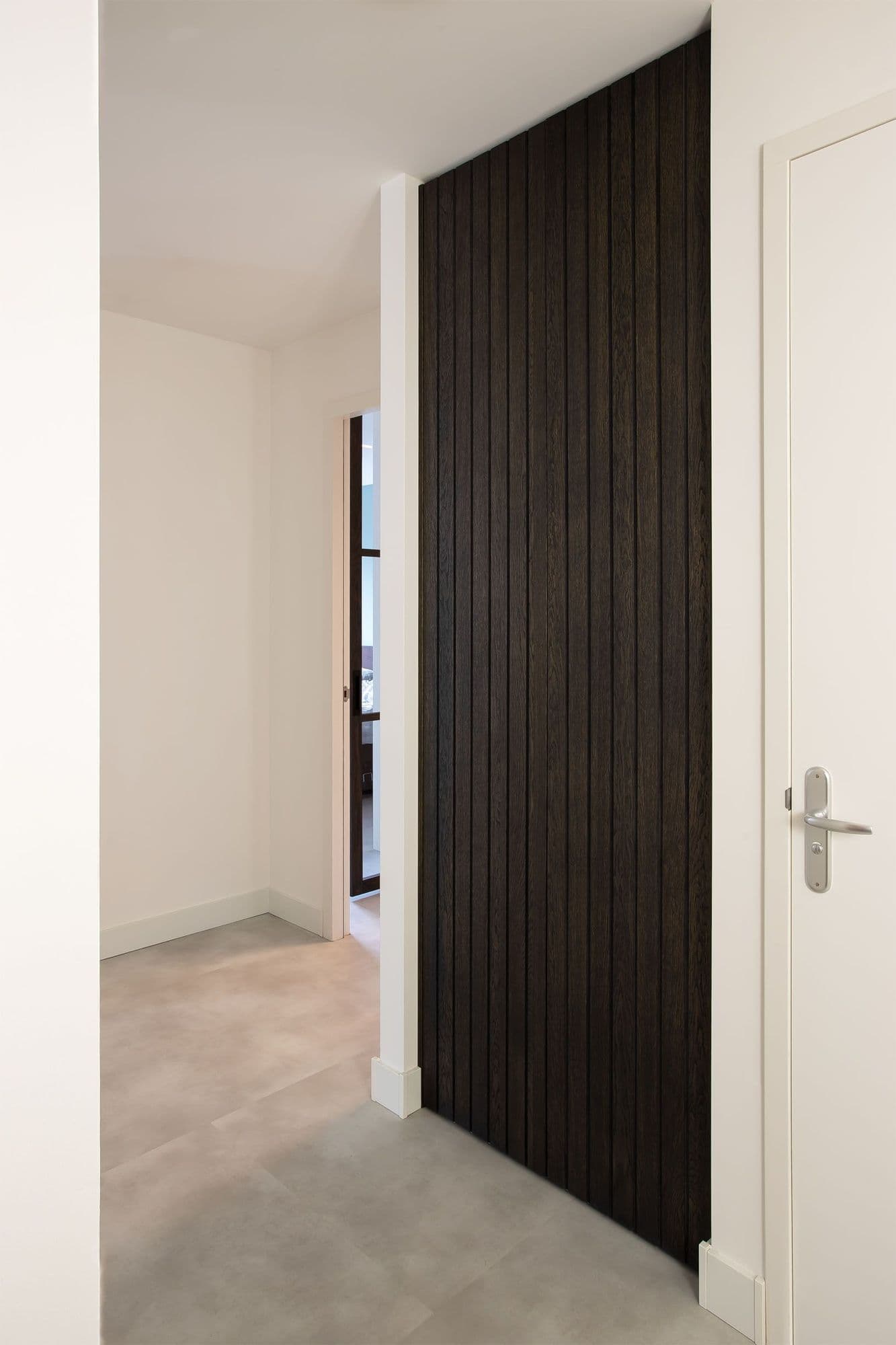 Ingebouwde garderobekast met lattenwand van geolied eiken in moderne hal.