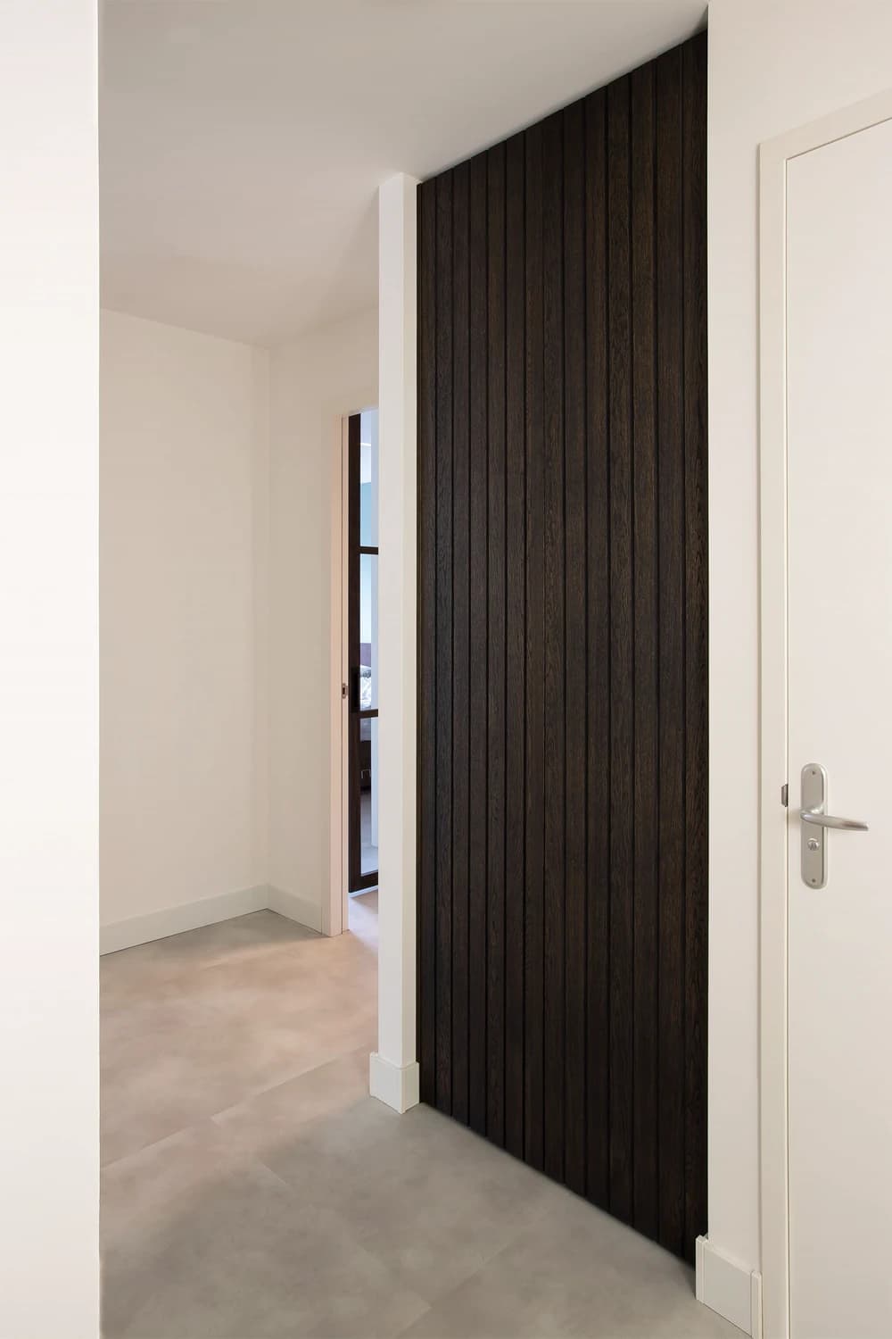 Ingebouwde garderobekast met lattenwand van geolied eiken in moderne hal.