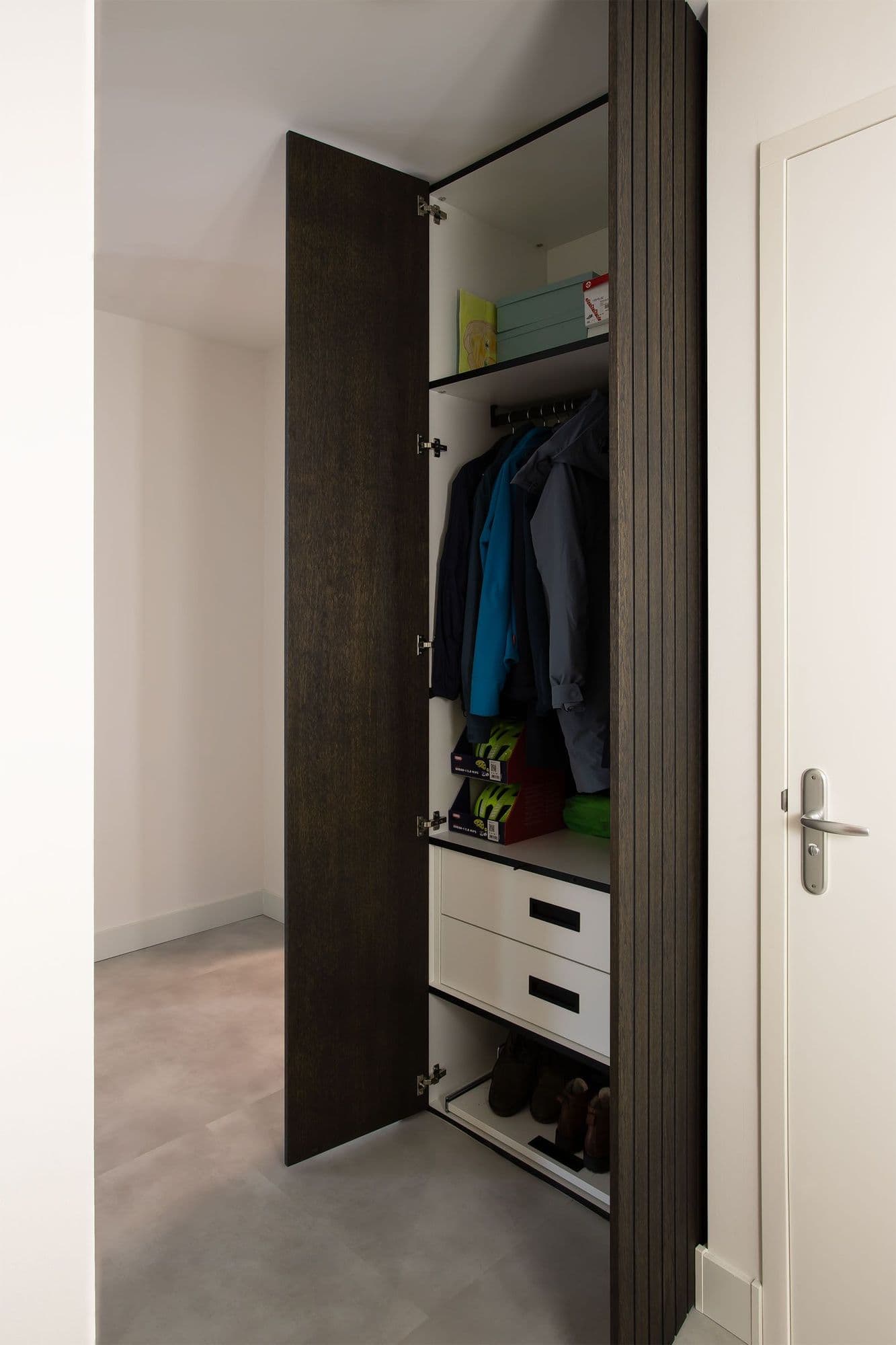 Opengeklapte garderobekast met lattenbekleding en opbergruimte voor jassen en schoenen.