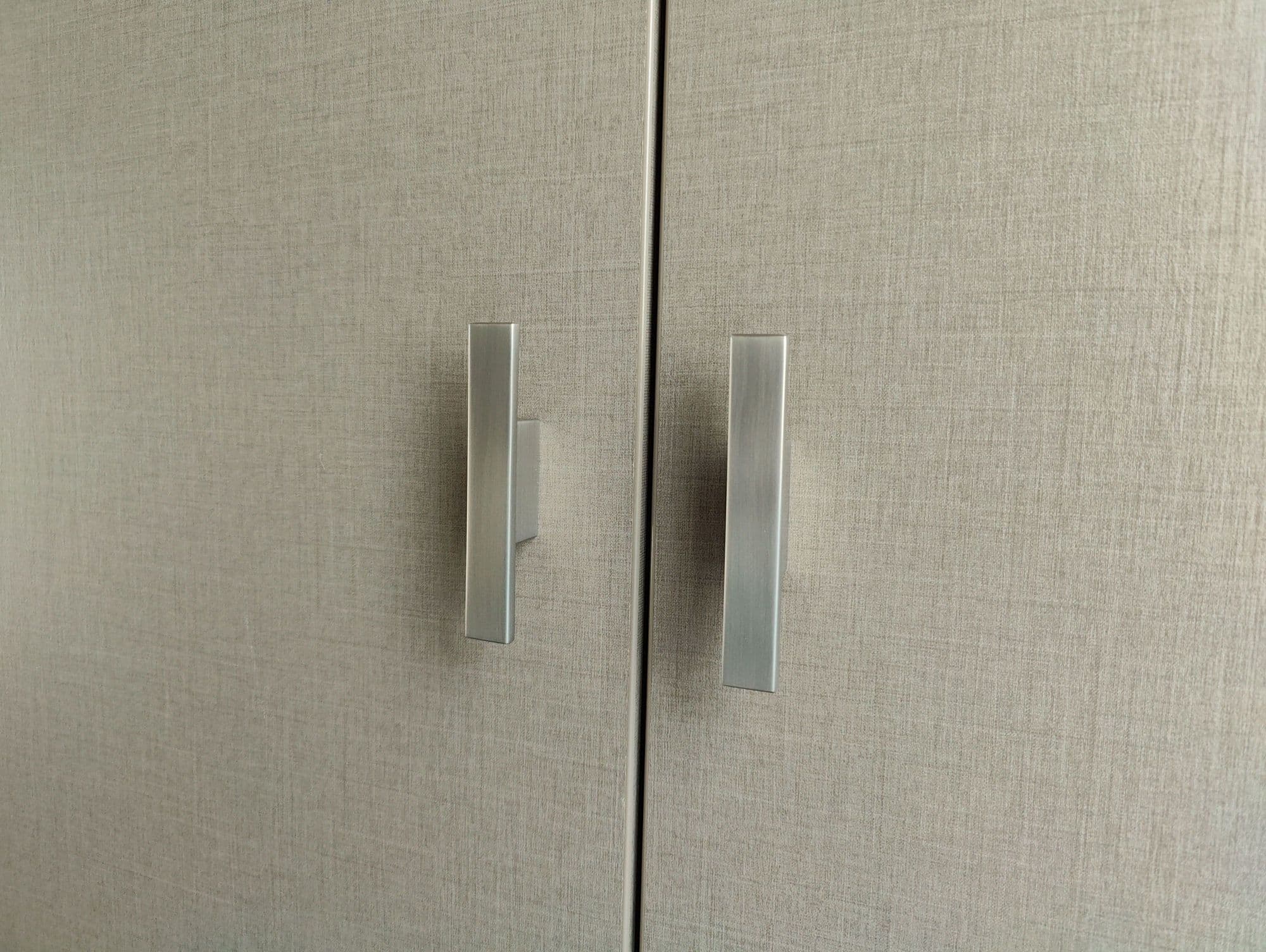 Close-up van de handgrepen van een moderne wasmachinekast gemaakt van Decolegno Cleaf decorplaat.