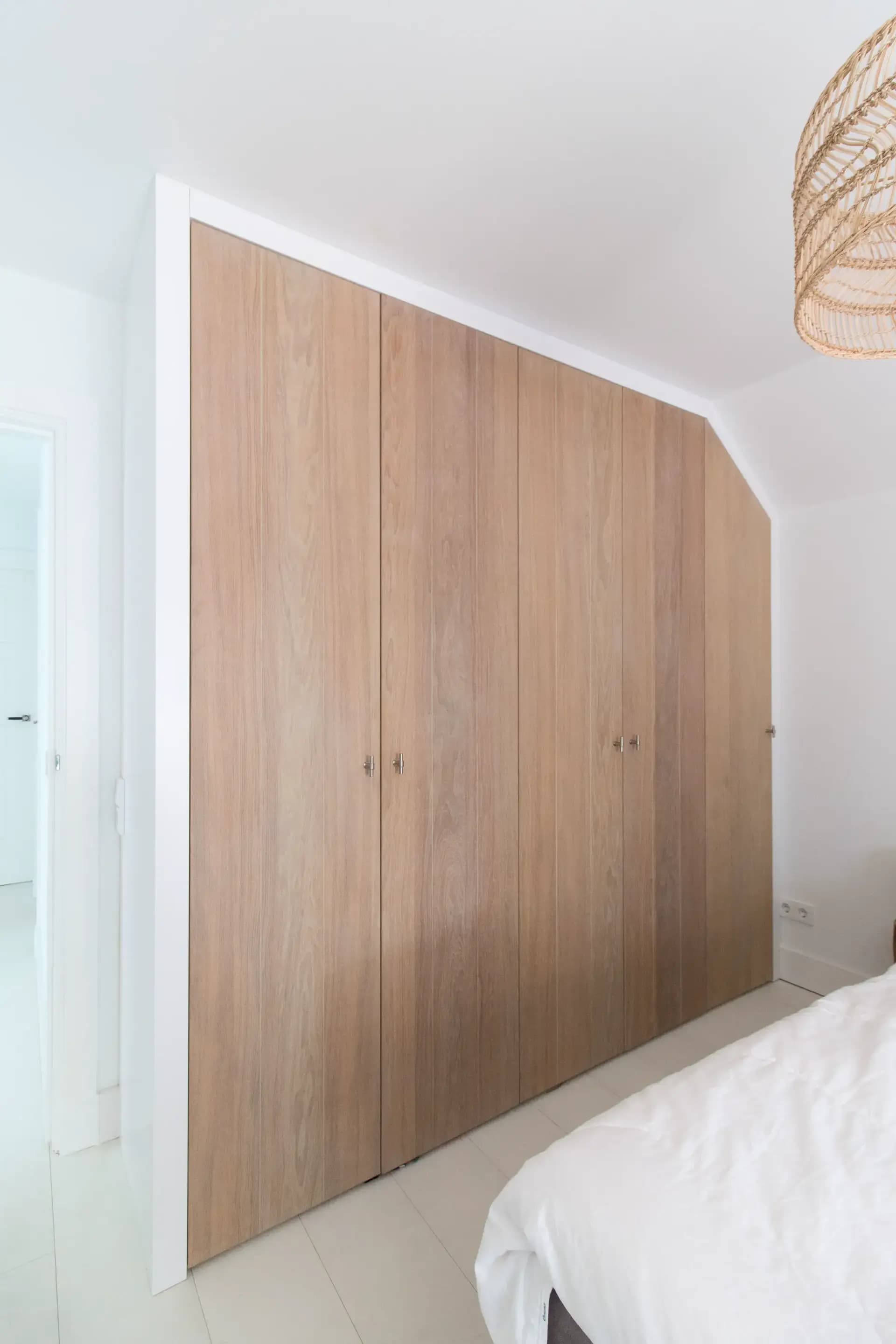 Moderne inbouw kledingkast met schuine hoek en rustiek eiken fineer in een slaapkamer in Veenendaal.