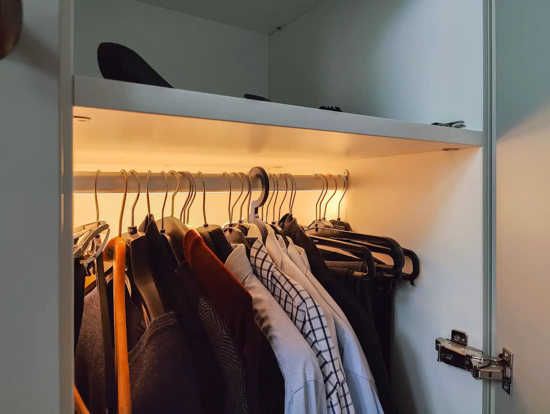 Lange gang van een klassieke, chique inloopkast met bronzen knoppen en ingebouwd zitje in Barneveld.