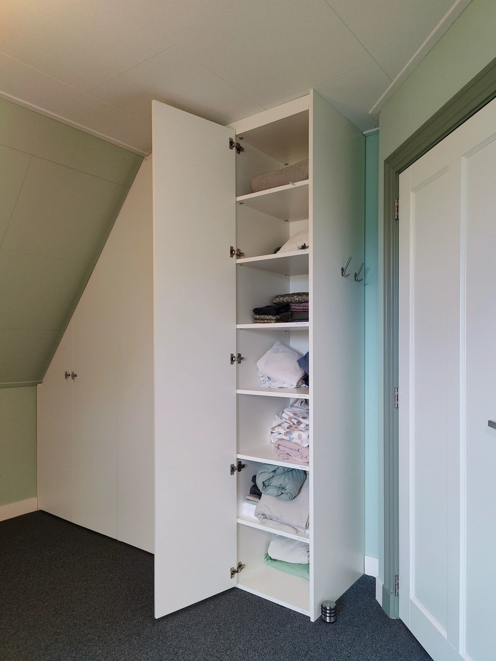 Witte kledingkast onder schuin dak met strakke afwerking in Kootwijkerbroek.