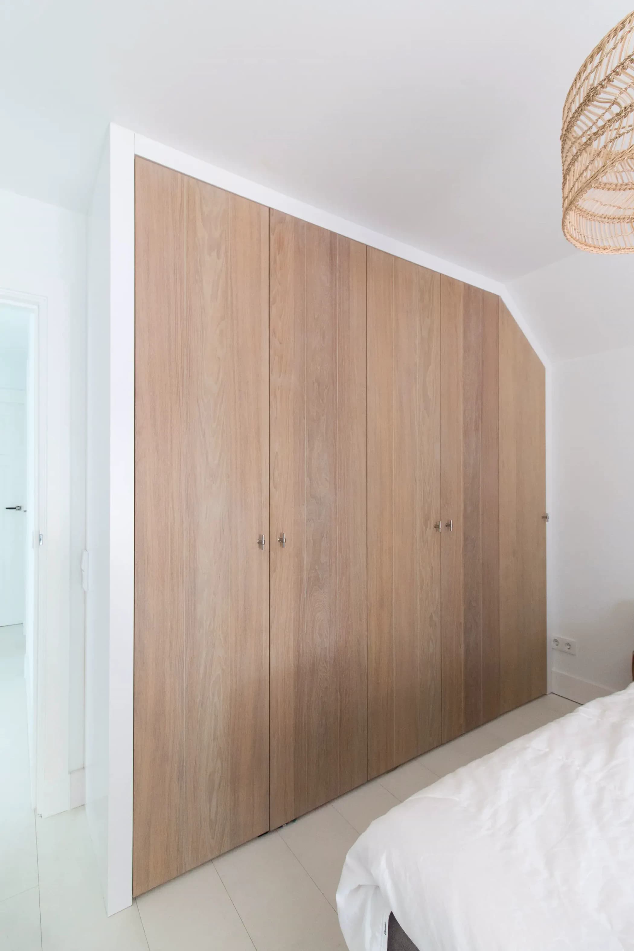 Moderne inbouw kledingkast met schuine hoek en rustiek eiken fineer in een slaapkamer in Veenendaal.