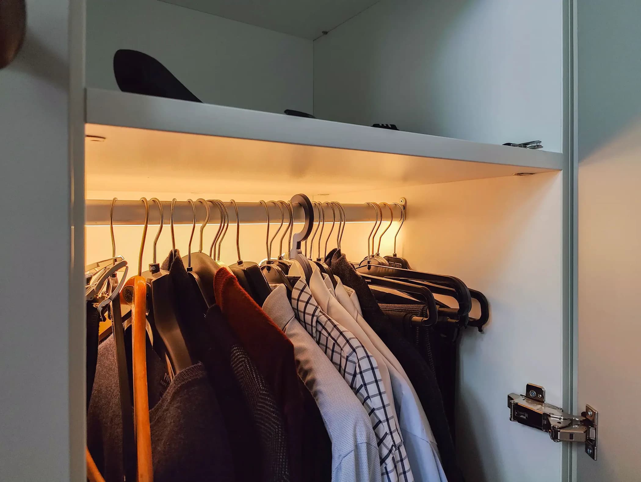 Lange gang van een klassieke, chique inloopkast met bronzen knoppen en ingebouwd zitje in Barneveld.