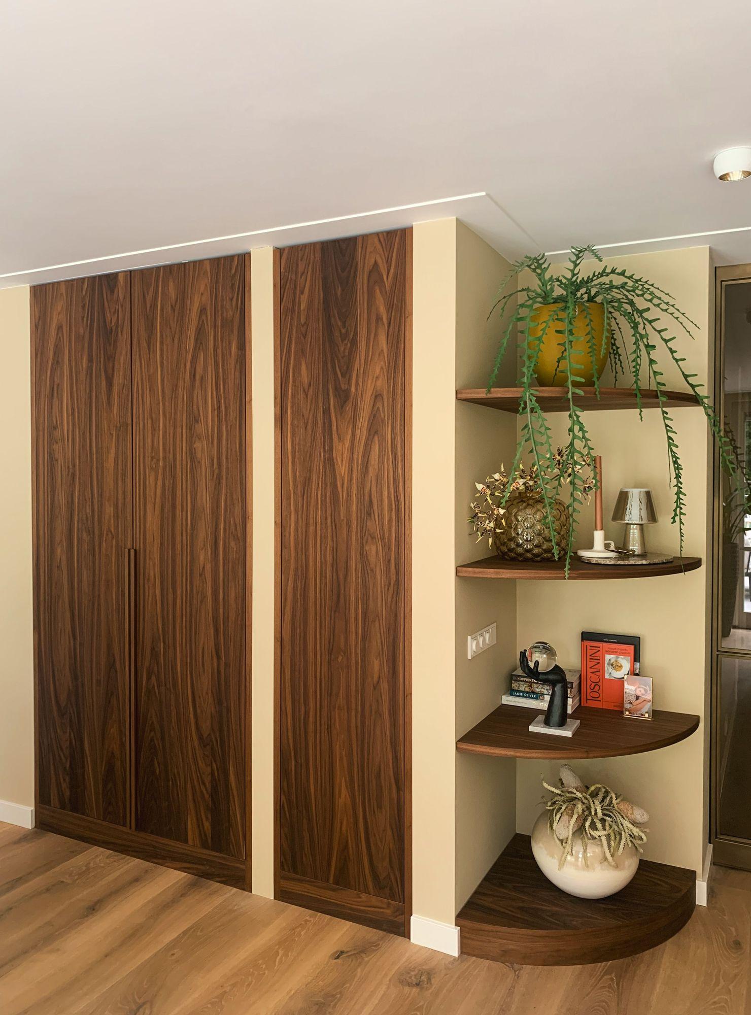 Volledig gefineerde notenhouten wandkast met artistieke ronde planken in een moderne woonkamer.