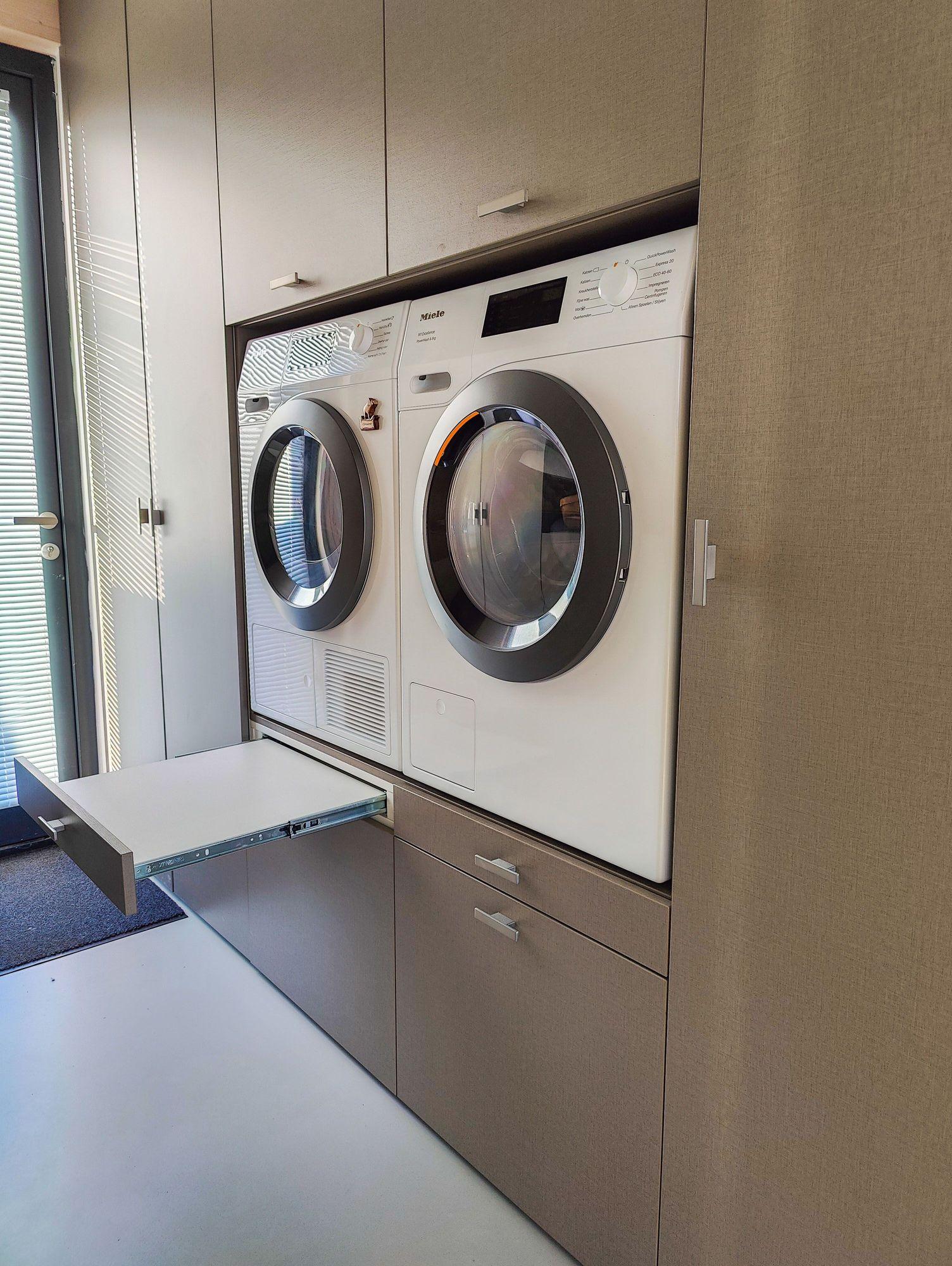 Moderne wasmachinekast met uittrekbare lade en ingebouwde wasmachine en droger in een bijkeuken in Almere.