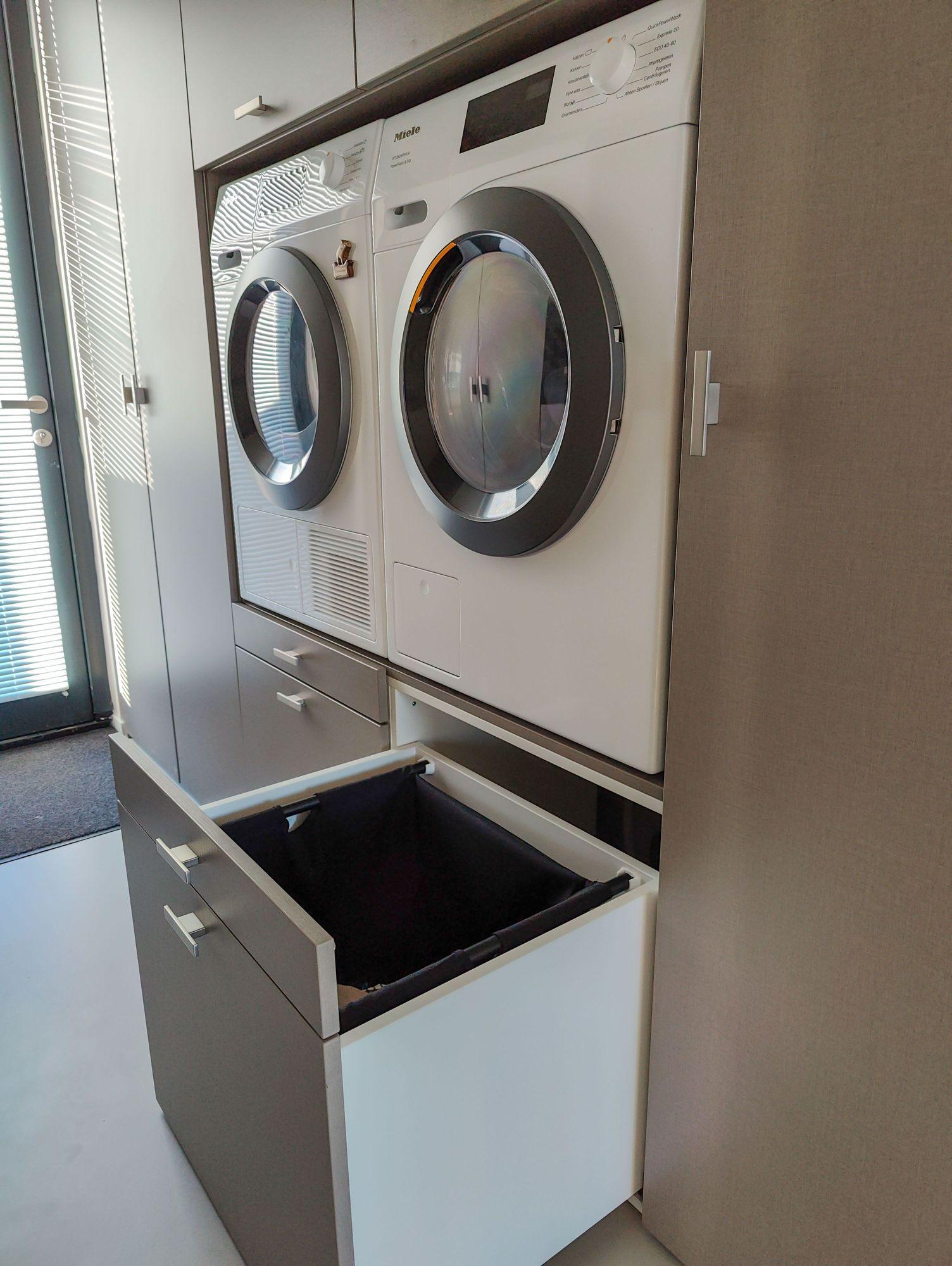 Ingebouwde wasmachine en droger met uittrekbare wasmand lade in een moderne wasmachinekast, geplaatst in een bijkeuken in Almere.