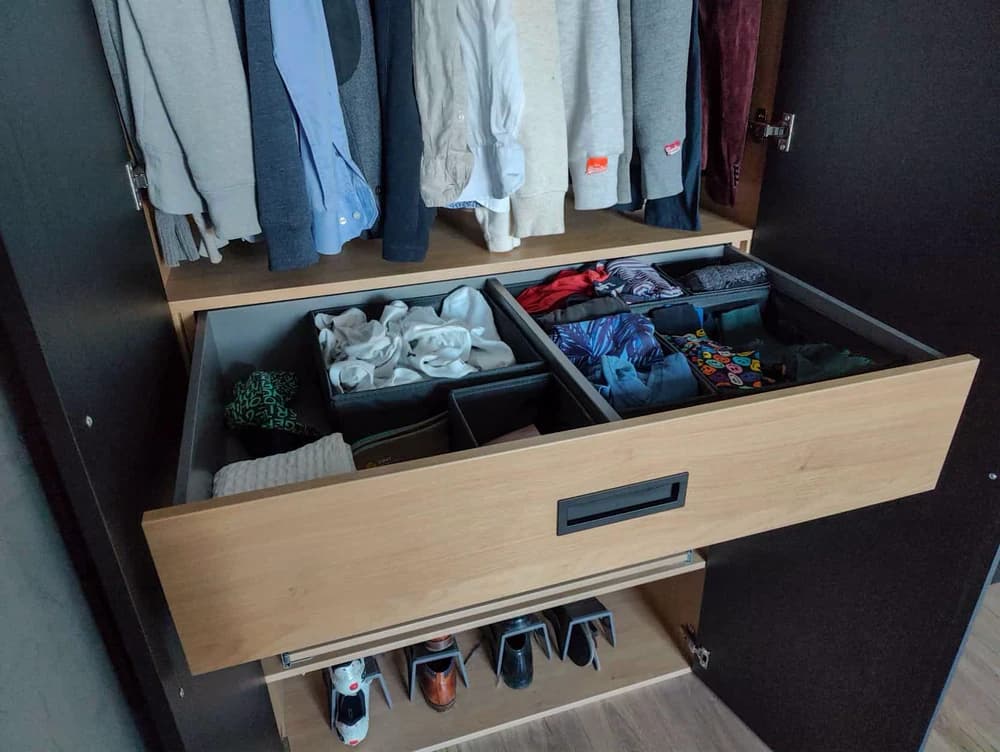 Lade met georganiseerde kleding en accessoires in een ingebouwde zwarte kledingkast in Blaricum.