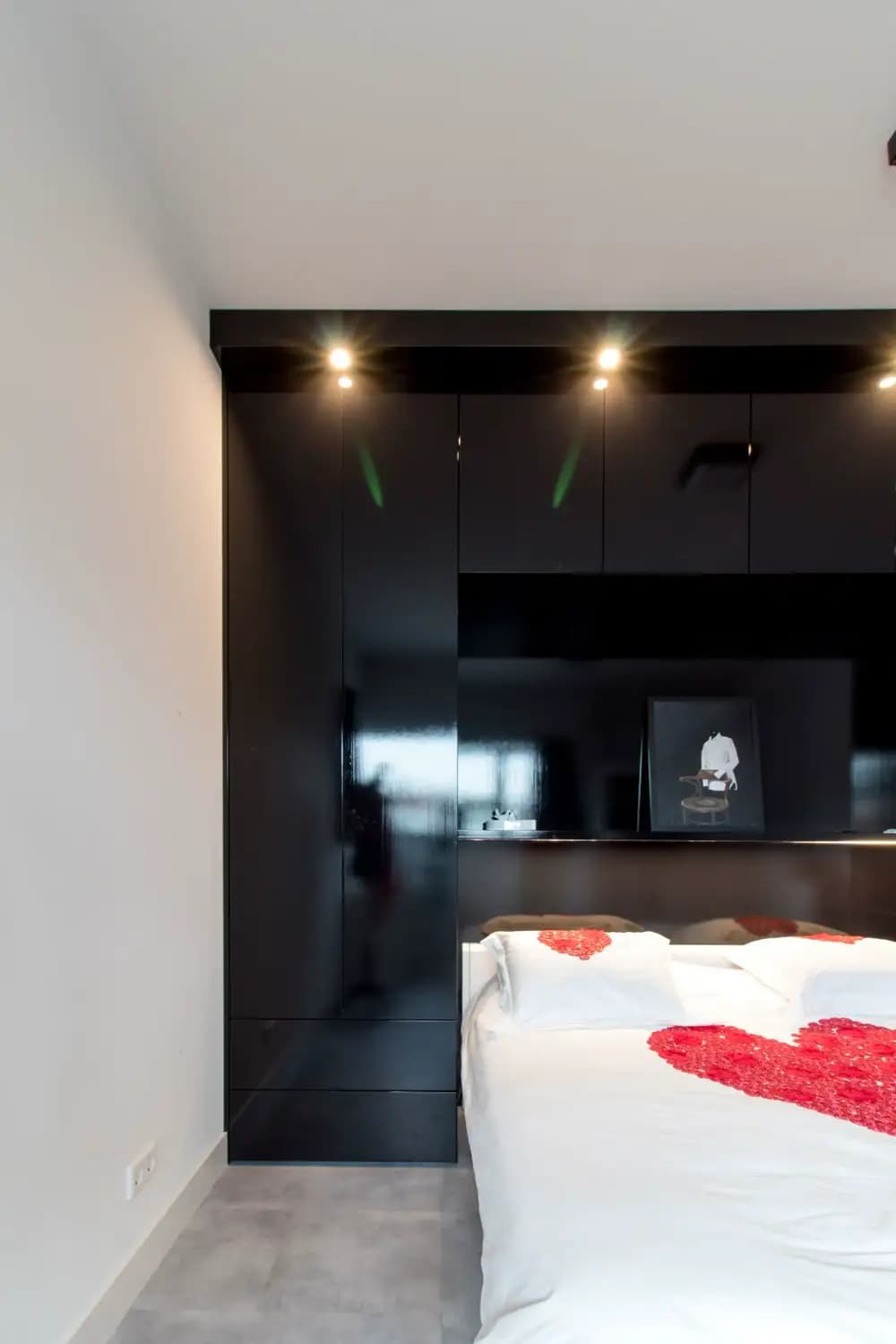 Klassieke zwarte hoogglans kledingkast met bedachterwand en ingebouwde verlichting in Ede.