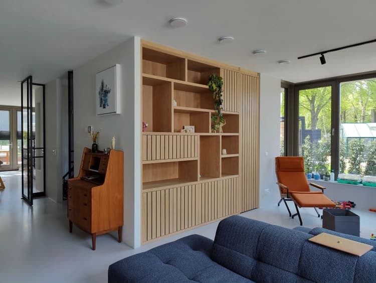 Trendy wandkast op maat met geolied eiken fineer en lattenbekleding in een woonkamer in Hilversum.