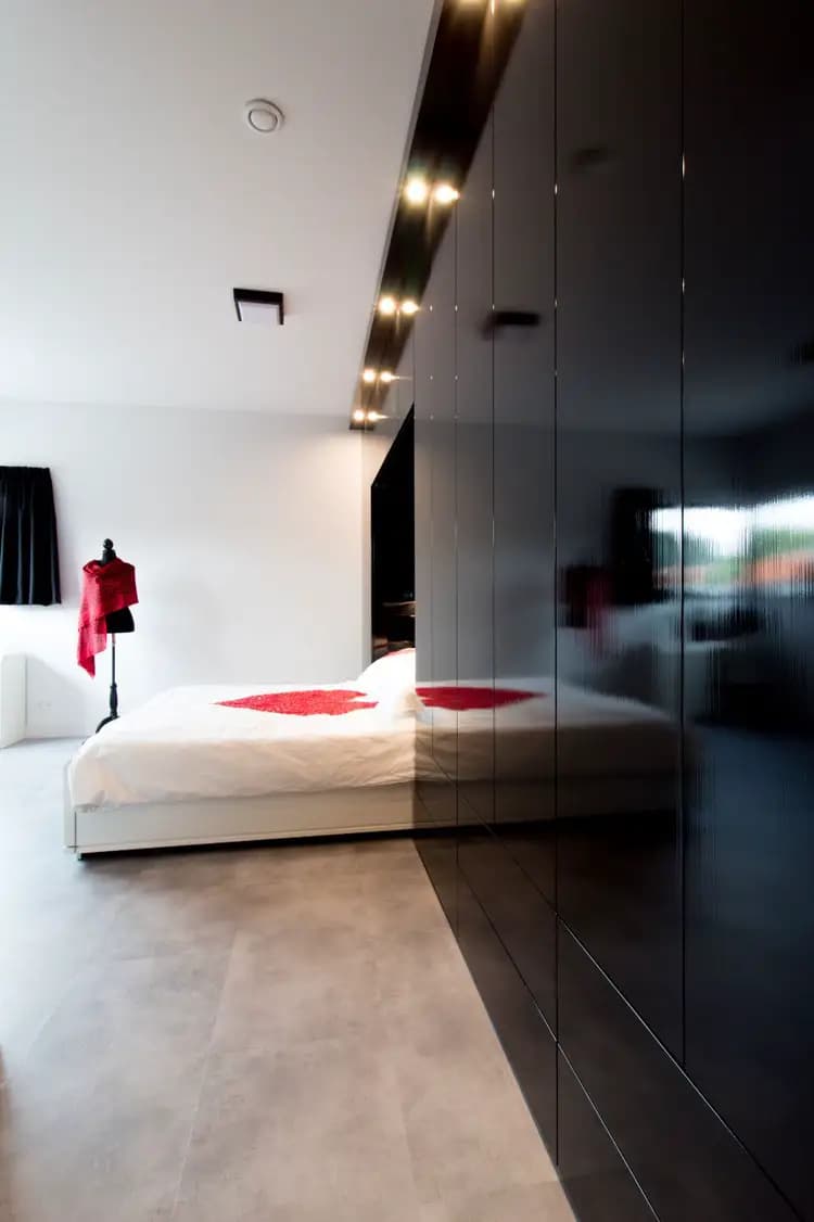 Zwarte hoogglans kledingkast rondom bed met ingebouwde verlichting in Ede.