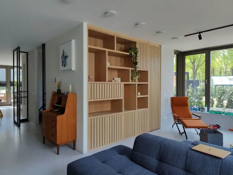 Trendy wandkast op maat met geolied eiken fineer en lattenbekleding in een woonkamer in Hilversum.