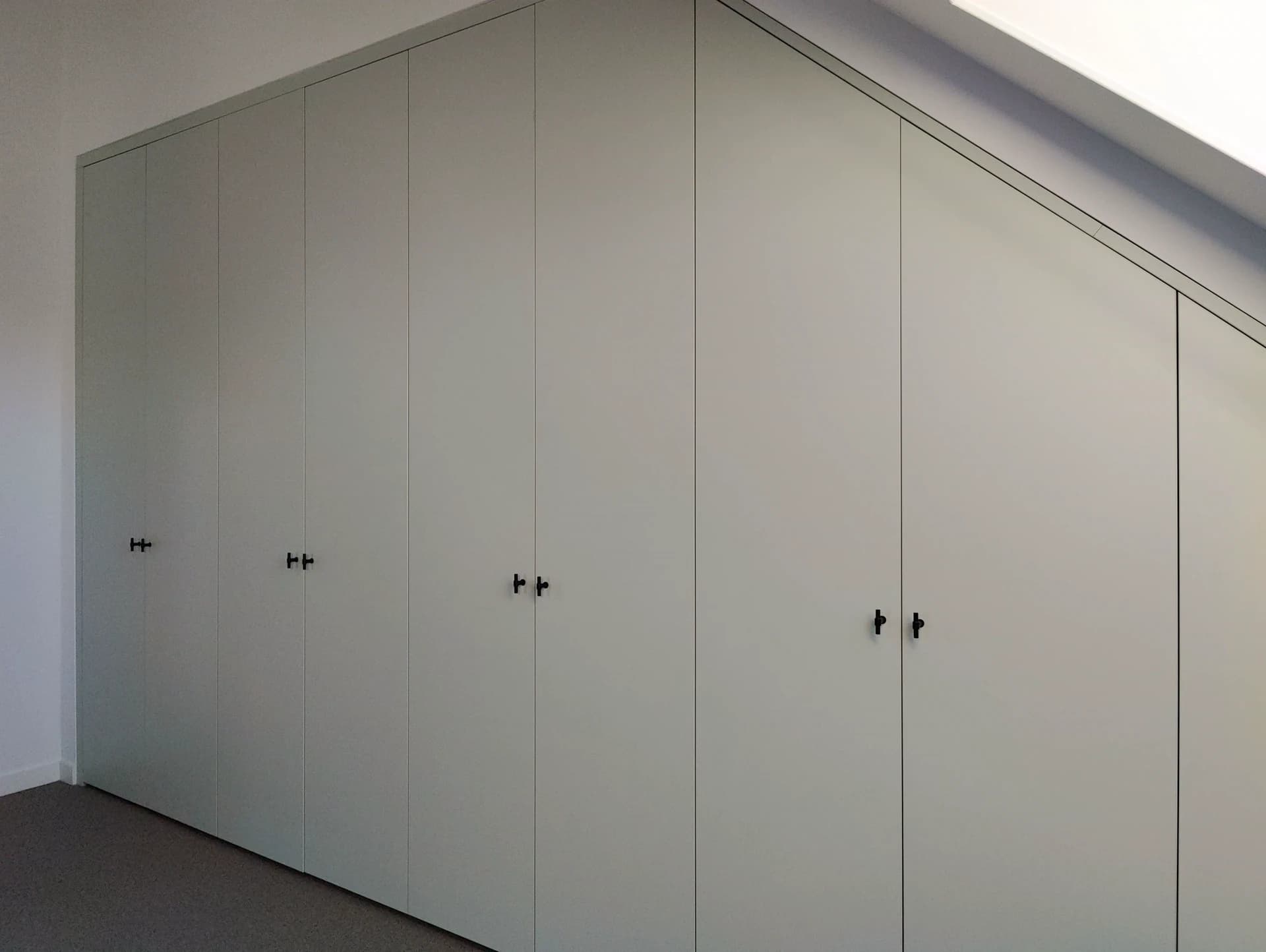 Detail van het schuin aflopende segment van de kledingkast met vouwdeuren.