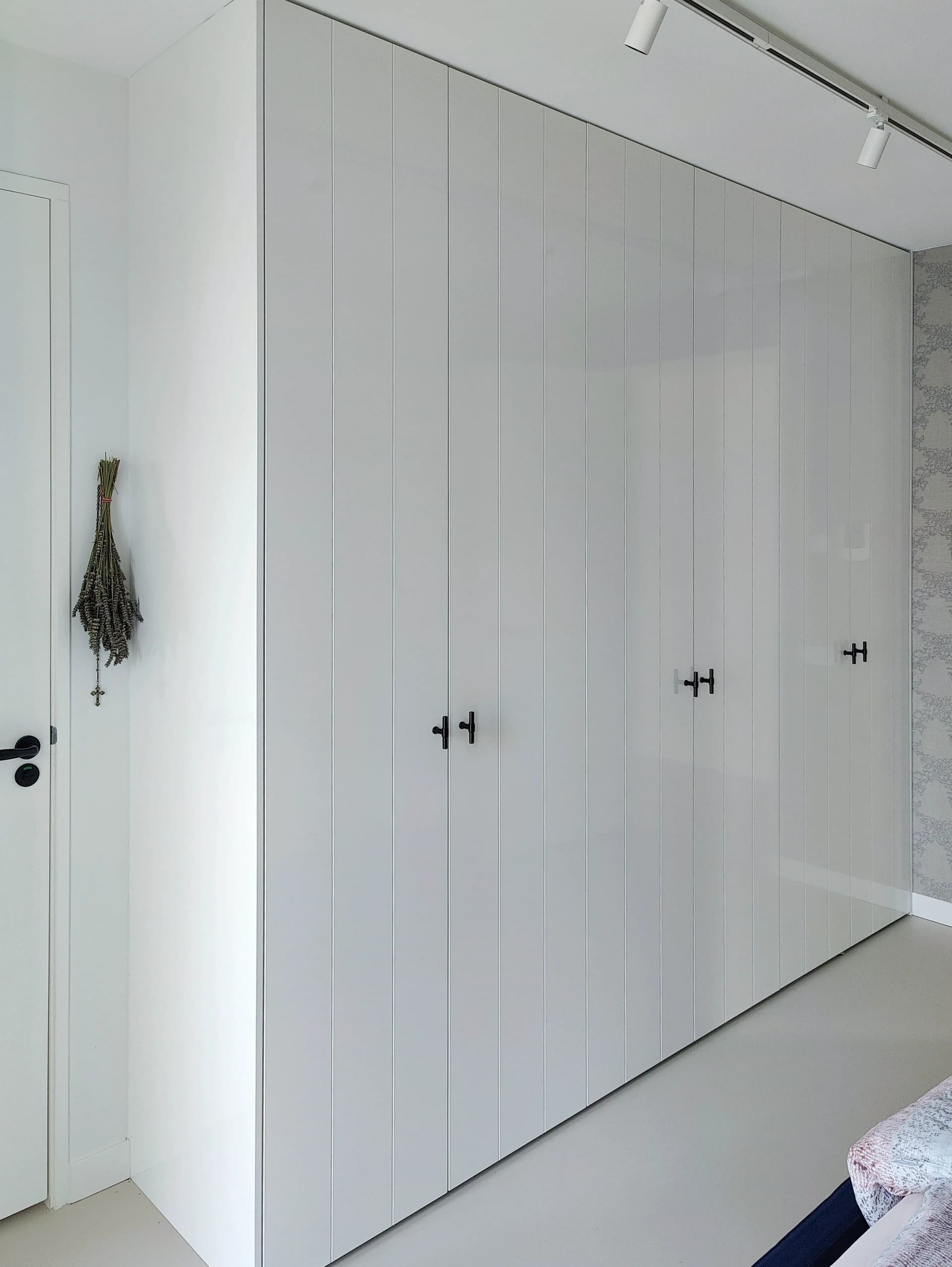 Dichtgeklapte witte hoogglans kledingkast met subtiele verticale lijnen.