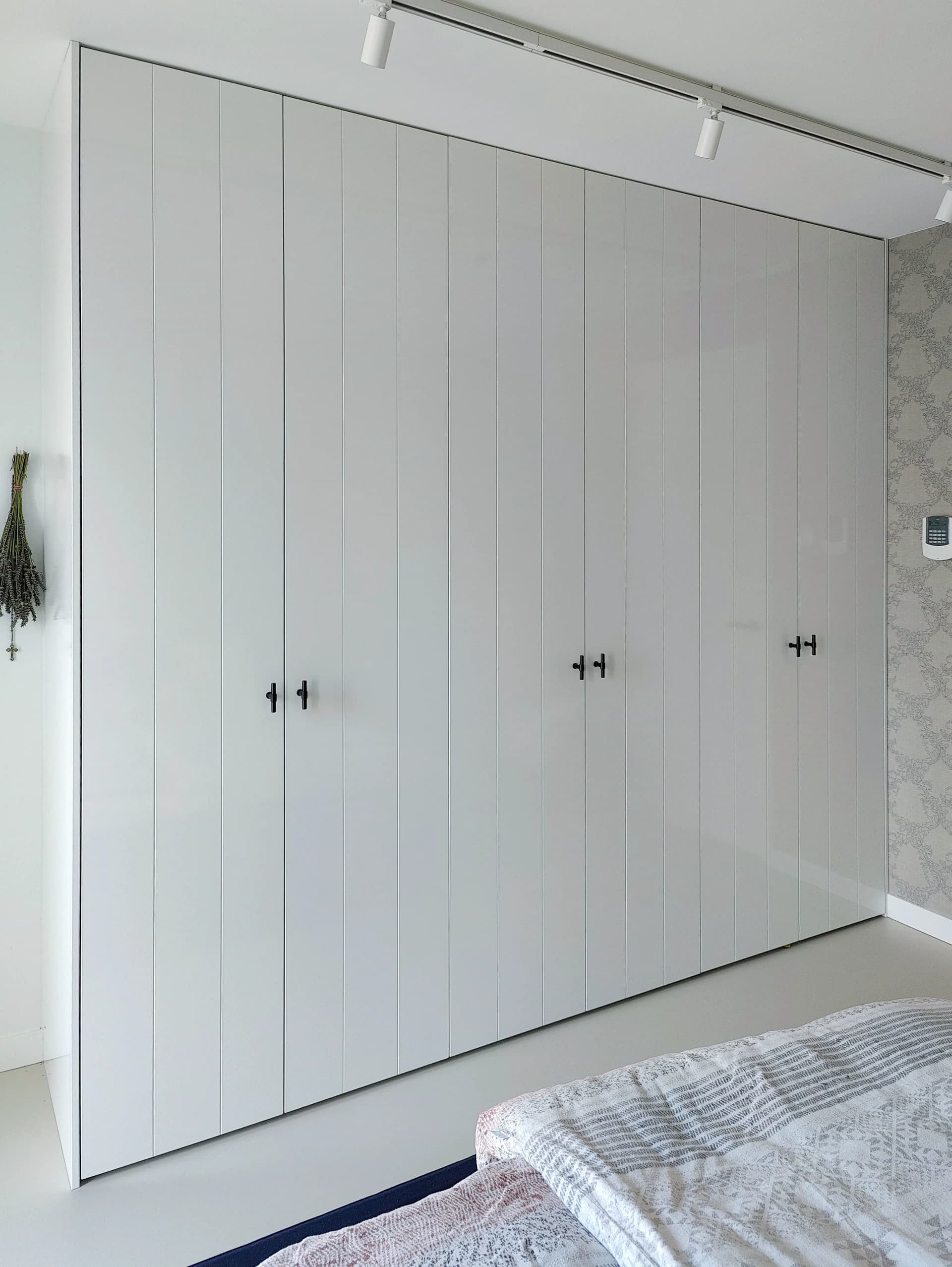 Strakke witte hoogglans kledingkast in een moderne slaapkamer in Putten.