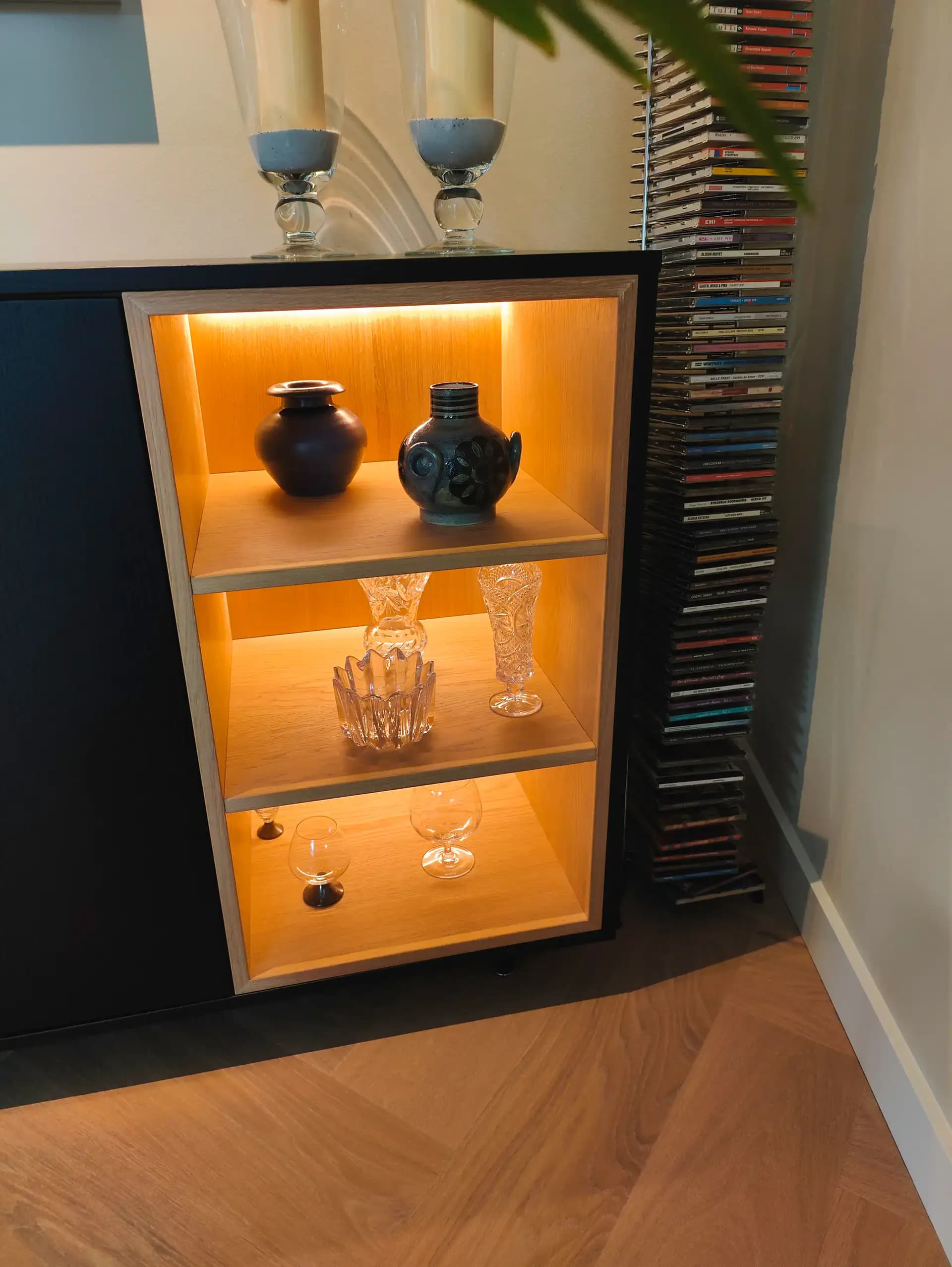 Detail van LED-verlichte eiken vakken in zwart dressoir op maat.