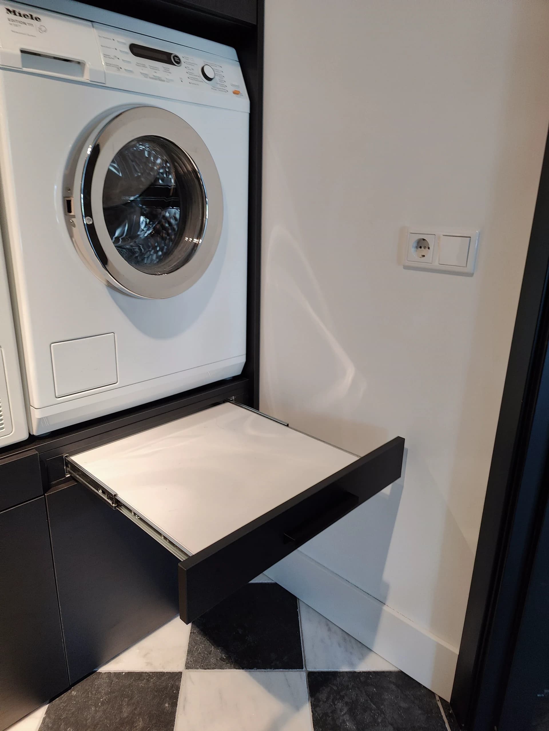 Uittrekbare plank voor wasmand in op maat gemaakte wasmachinekast in Blaricum.