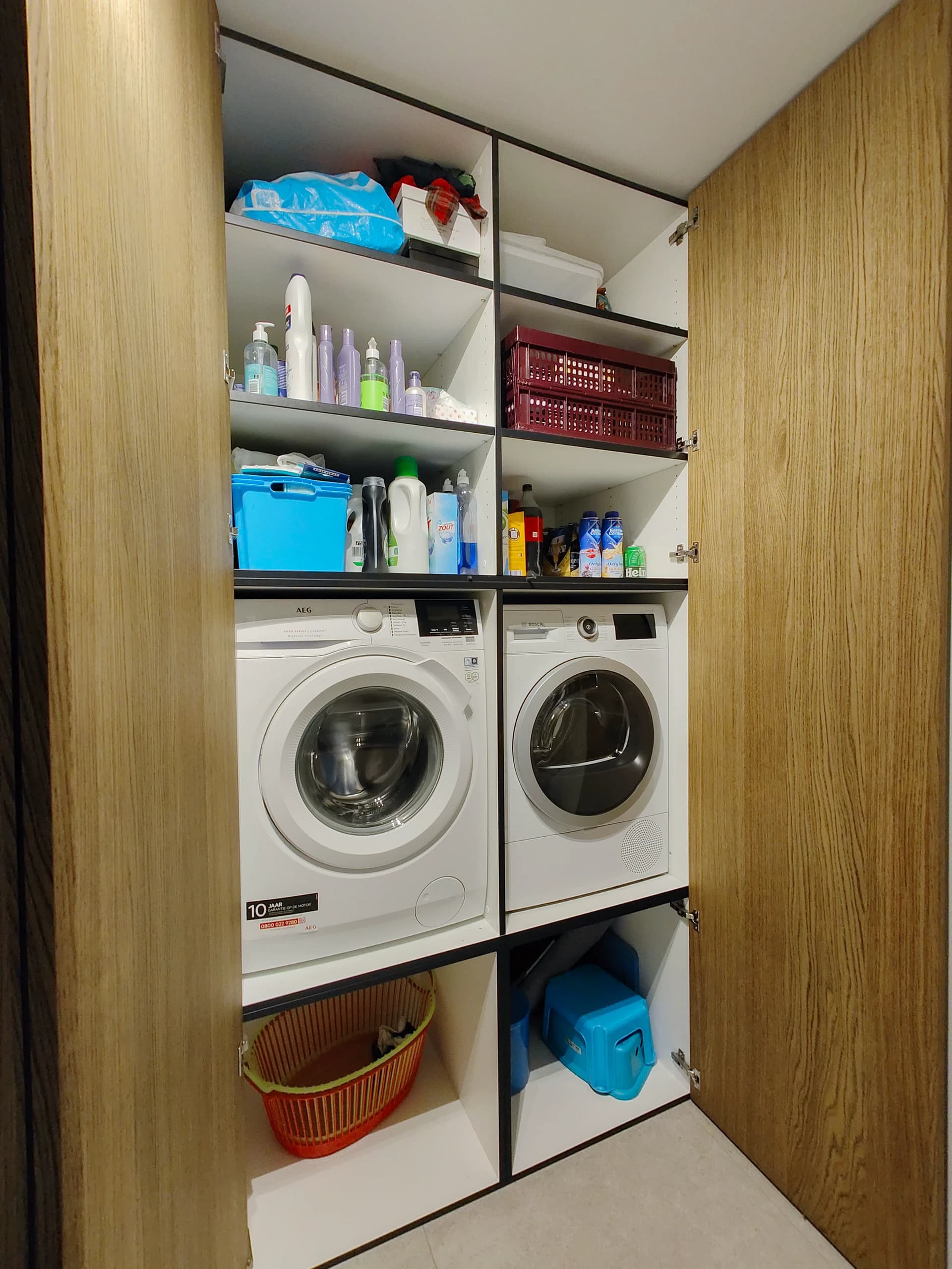 Ingebouwde wasmachines en opbergruimte in exclusieve houten bijkeukenkast.