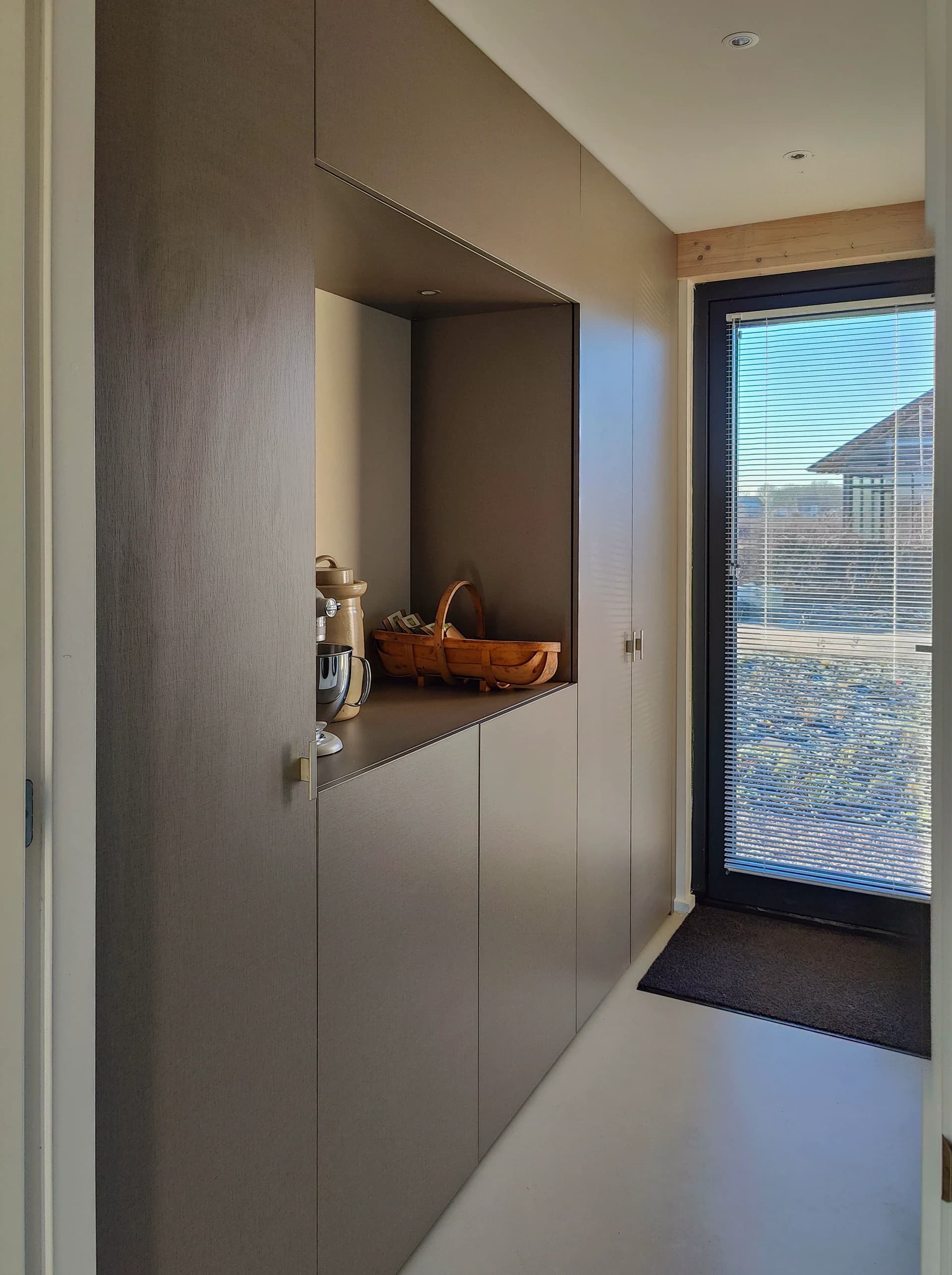 Zijaanzicht van een moderne wasmachinekast met geïntegreerde opbergruimte en spoelbak, in een bijkeuken in Almere.