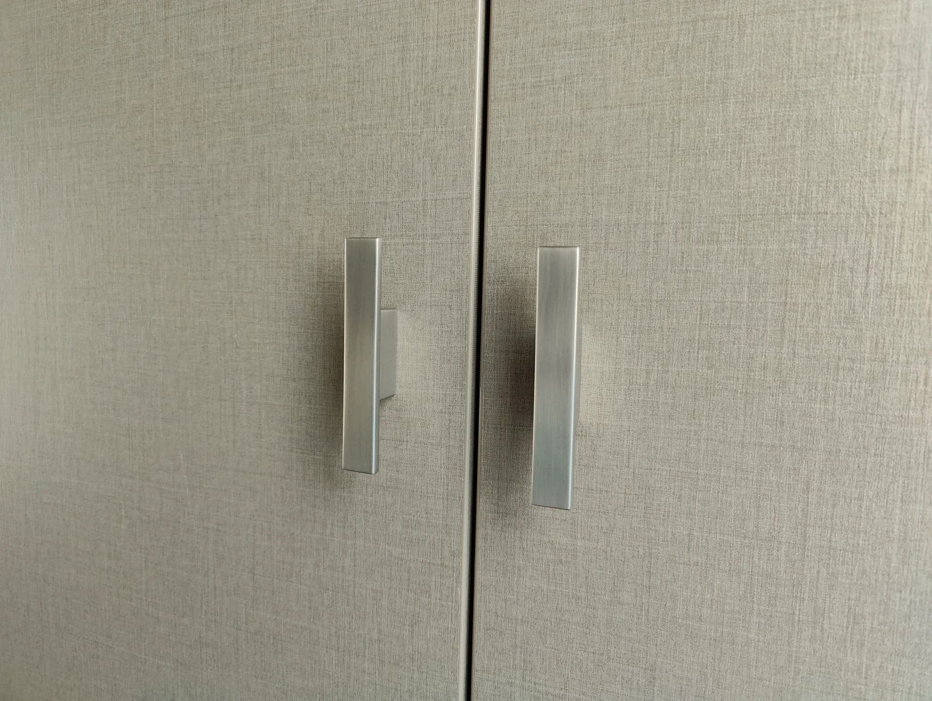 Close-up van de handgrepen van een moderne wasmachinekast gemaakt van Decolegno Cleaf decorplaat.