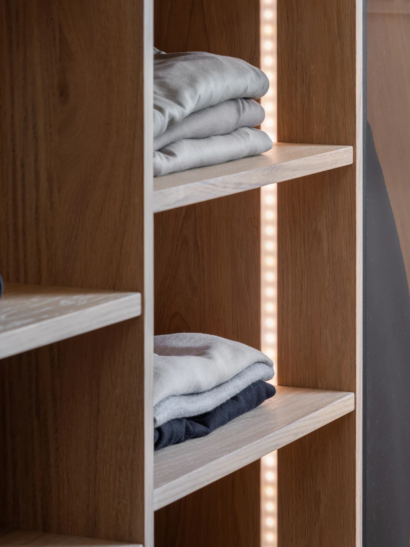 4. Kledingkast op maat met openstaande glazen draaideuren en een hanggedeelte voor jassen en andere kleding.