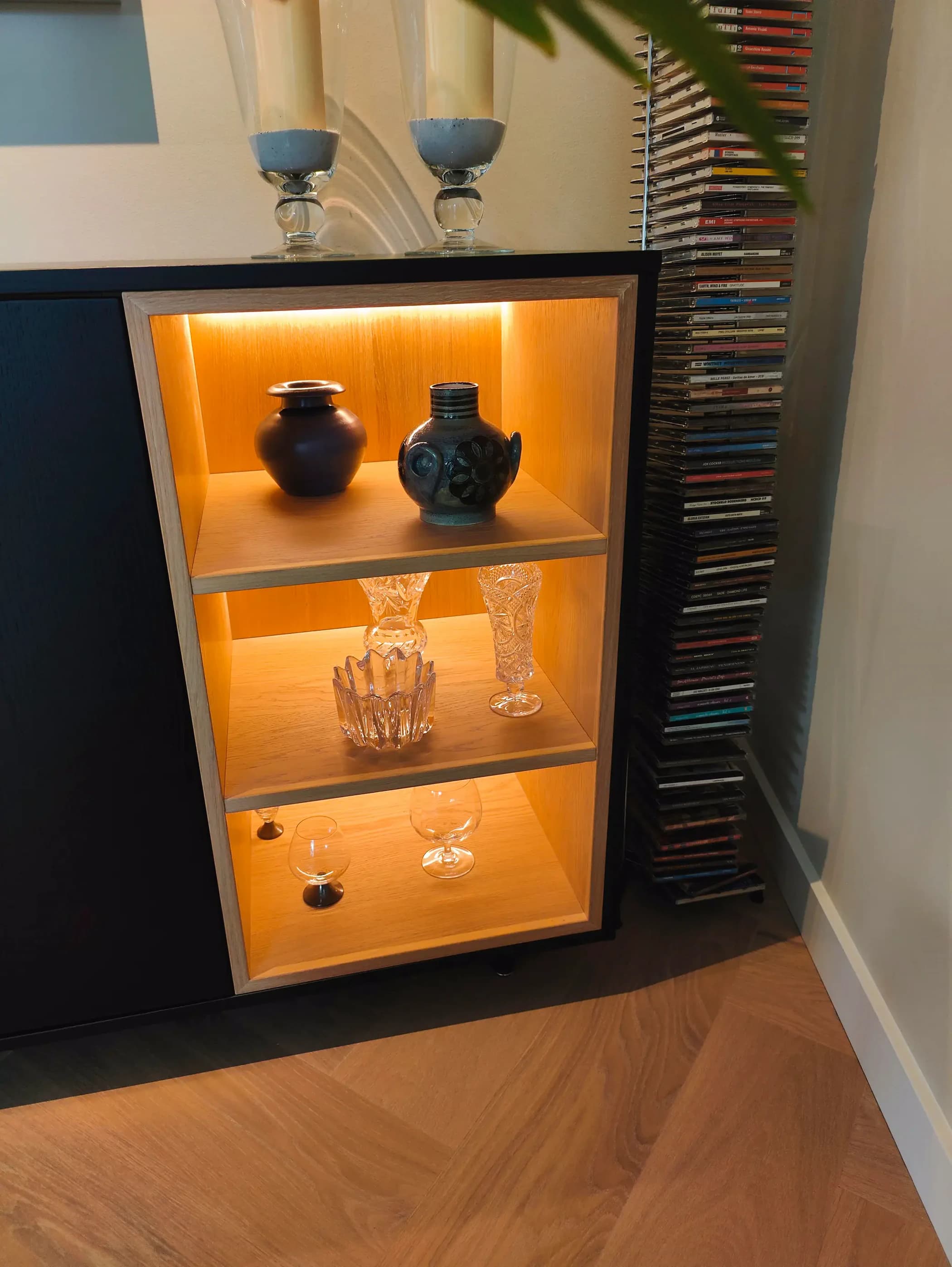 Detail van LED-verlichte eiken vakken in zwart dressoir op maat.