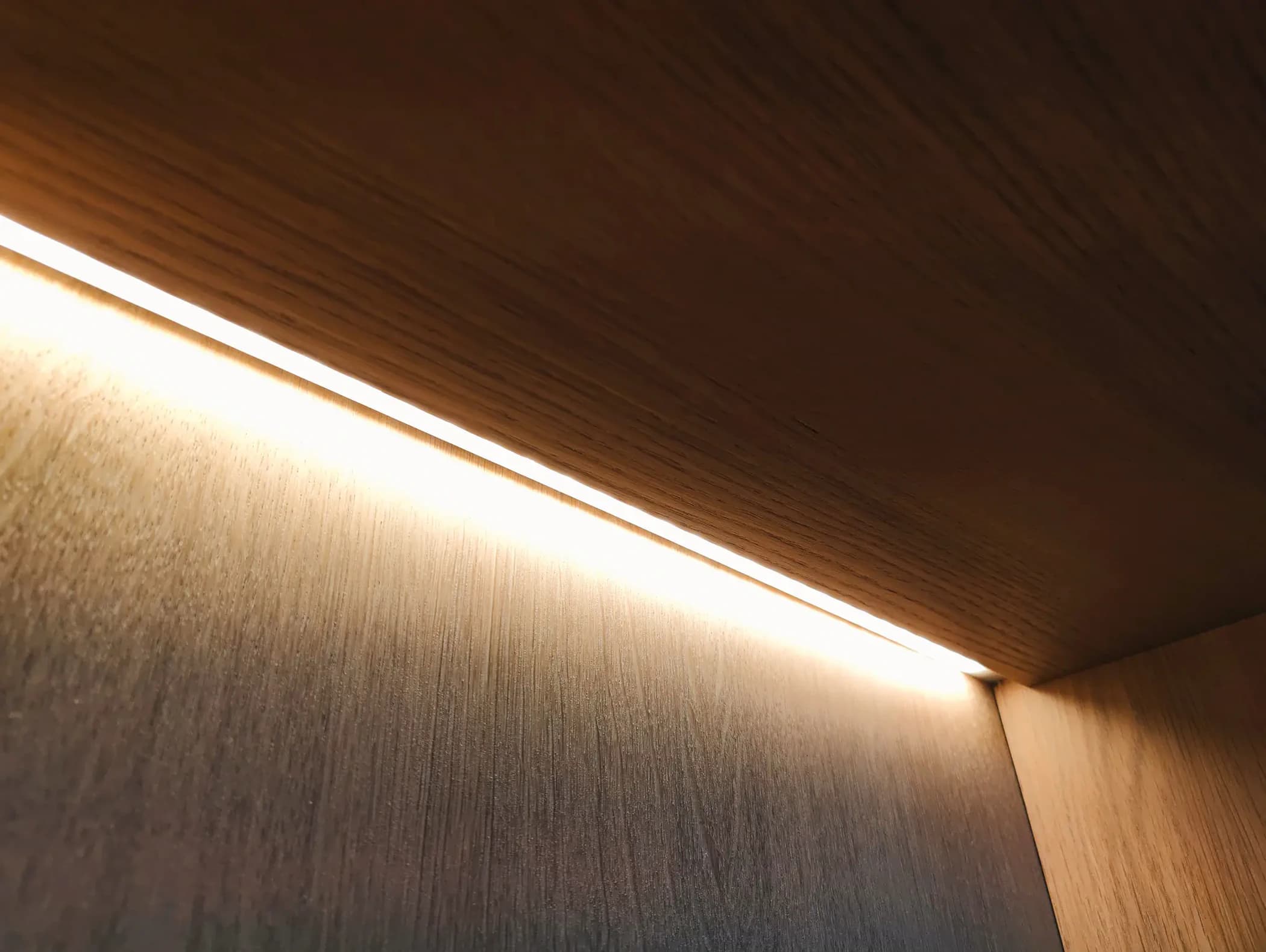 Dimbare ledstrips in houten legplanken van op maat gemaakte kast